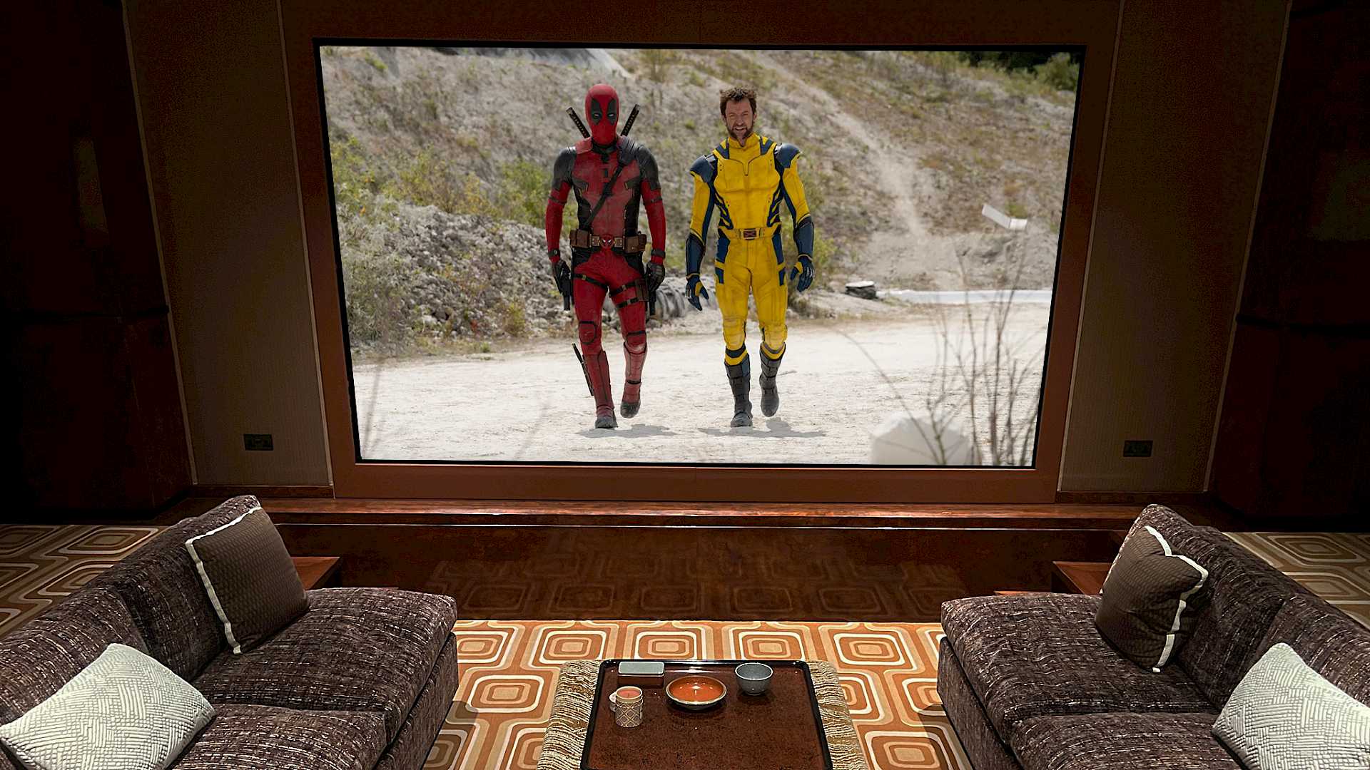 Shows home cinema screen from seating position, with coffee table and Marvel film on screen.