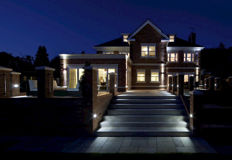 Rear of house with outside lighting and house lights on. Lighting controlled with a system that has had an upgrade to Lutron Homeworks QS.