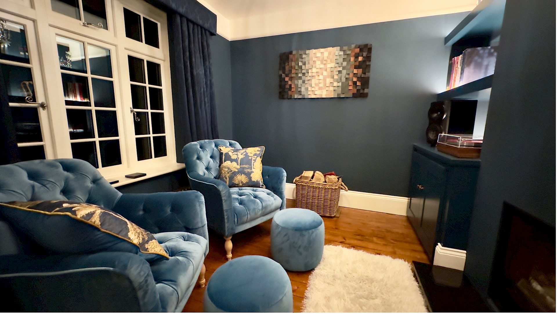A high performance listening room at a Kent project. This image shows blue seating in a small moody blue room.