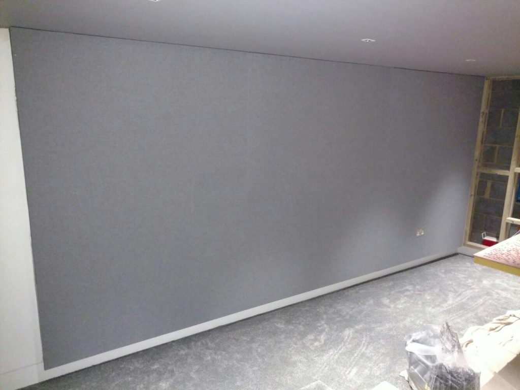 Shows grey stretched fabric covering the side wall and hiding the speaker and acoustic treatment.