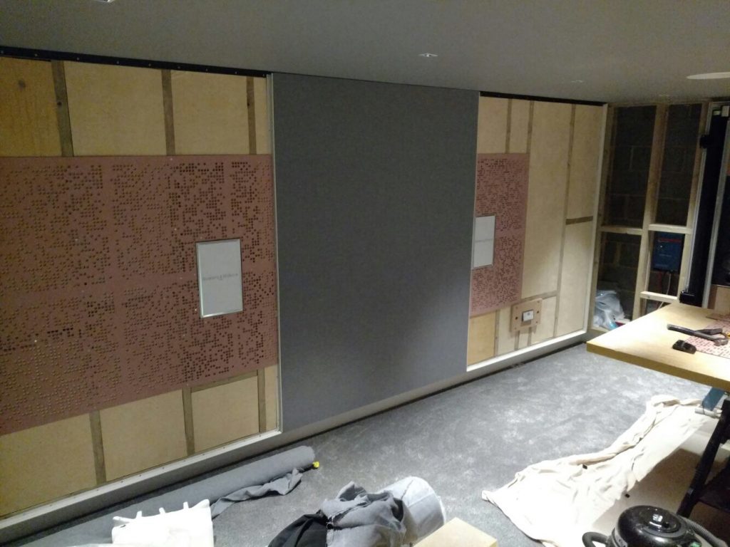 Image shows the home cinema side wall and acoustic treatment, with stretched fabric being installed.