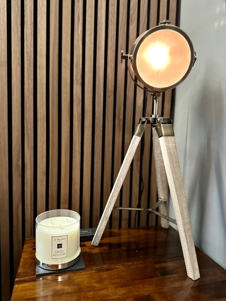 Image shows table lamp with candle, against an acoustic panel background.